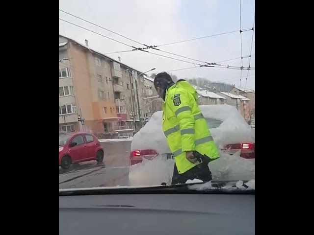 VIDEO Un polițist de la Rutieră deszăpezește luneta unei mașini aflate în trafic, în municipiul Brașov