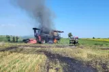 Combină agricolă cuprinsă de flăcări pe un câmp din judeţul Braşov